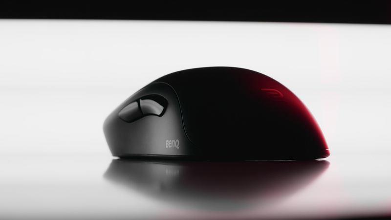 Black gaming mouse on a white surface with a thin red edge light and soft reflection