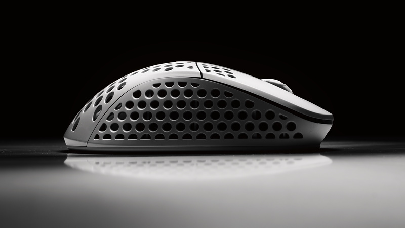 White honeycomb-shell gaming mouse rim-lit on black with a mirror reflection